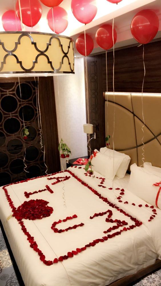 اتاق خواب عروسی که تخت آن با استفاده از گلبرگ های رز قرمز به شکل قلب و سقف آن با بادکنک های هلیومی قرمز رنگ تزیین شده است